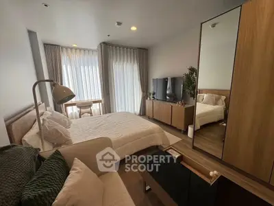 Modern bedroom with stylish decor, large window, and cozy seating area.