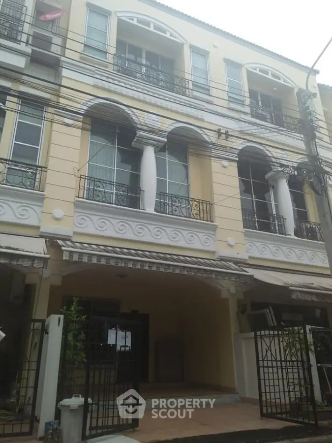 Elegant three-story townhouse with classic architectural details and gated entrance.