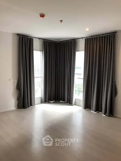 Spacious corner unit with large windows and elegant curtains in a modern apartment.