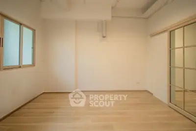 Spacious empty room with wooden flooring and mirrored closet doors, ideal for customization.
