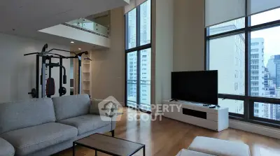 Spacious modern living room with city view and home gym equipment, featuring large windows and sleek furniture.
