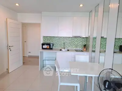 Modern kitchen with sleek white cabinets and green mosaic backsplash in a stylish apartment.
