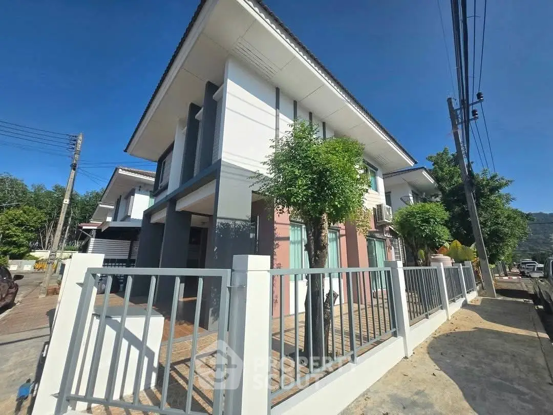 Modern two-story house with sleek design and fenced yard under clear blue sky.