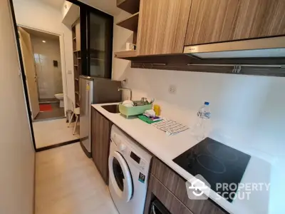 Modern kitchen with sleek appliances and compact design, featuring washing machine and electric stove.