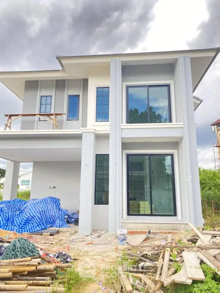 Modern two-story house under construction with large windows and a spacious design.