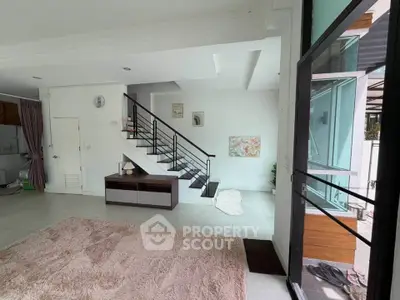 Spacious modern living room with staircase and large windows, perfect for natural light lovers.