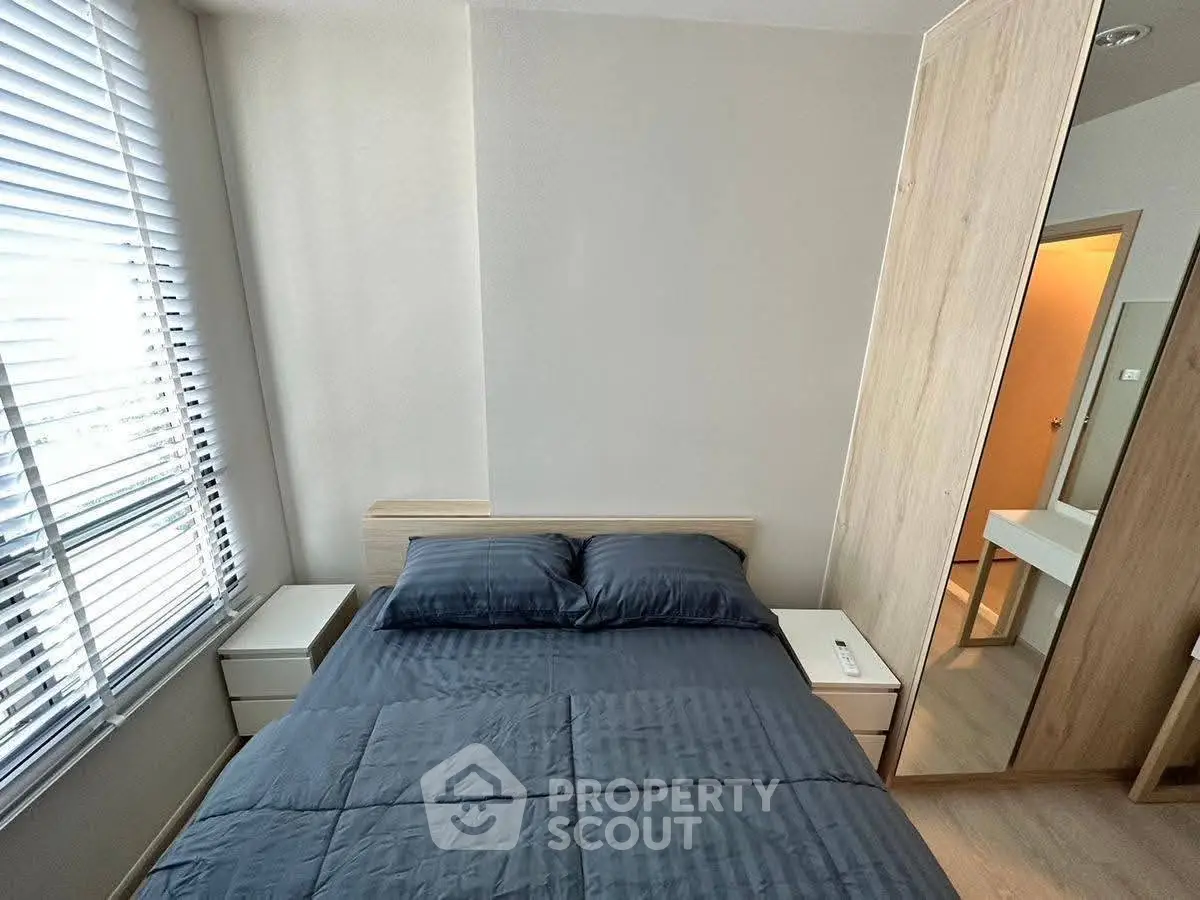Modern bedroom with sleek design, featuring a cozy bed and ample natural light from large windows.