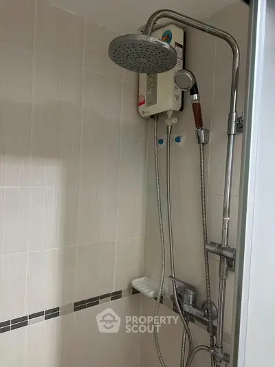 Modern bathroom shower with sleek fixtures and water heater in a stylish tiled setting.