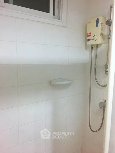 Compact bathroom with shower and water heater, ideal for small spaces.