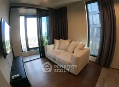 Modern living room with large windows and cozy sofa in a high-rise apartment.