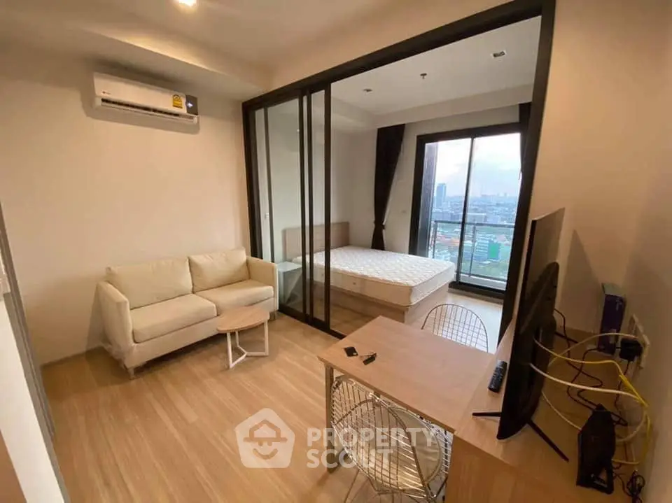 Modern studio apartment with city view, featuring a cozy living area and bedroom with large windows.