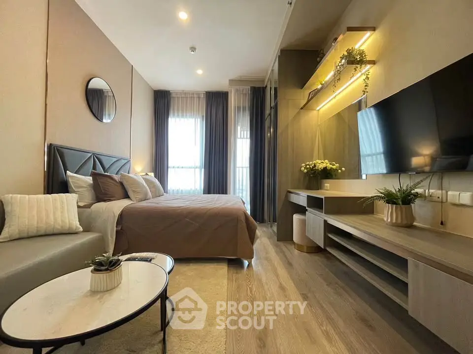 Modern bedroom with stylish decor, cozy seating area, and large TV, perfect for relaxation.