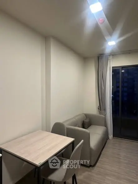 Cozy modern living room with sofa and dining table, featuring large window for natural light.