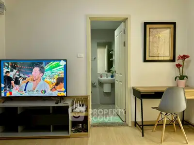 Cozy living room with TV, desk, and view into a modern bathroom, perfect for urban living.