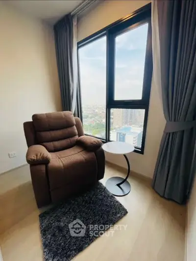 Cozy reading nook with plush armchair and city view from high-rise window.