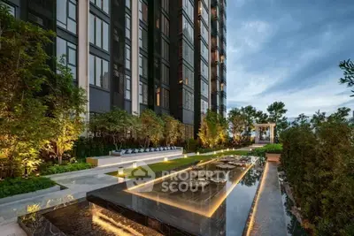 Luxurious modern building exterior with elegant garden and water feature at dusk.
