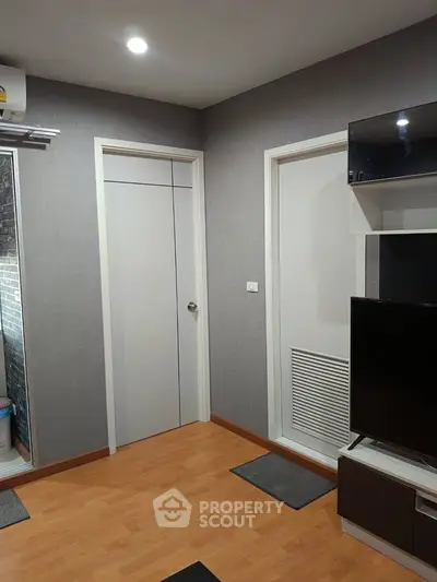 Modern living room with sleek design and wooden flooring, featuring a wall-mounted TV and air conditioning.