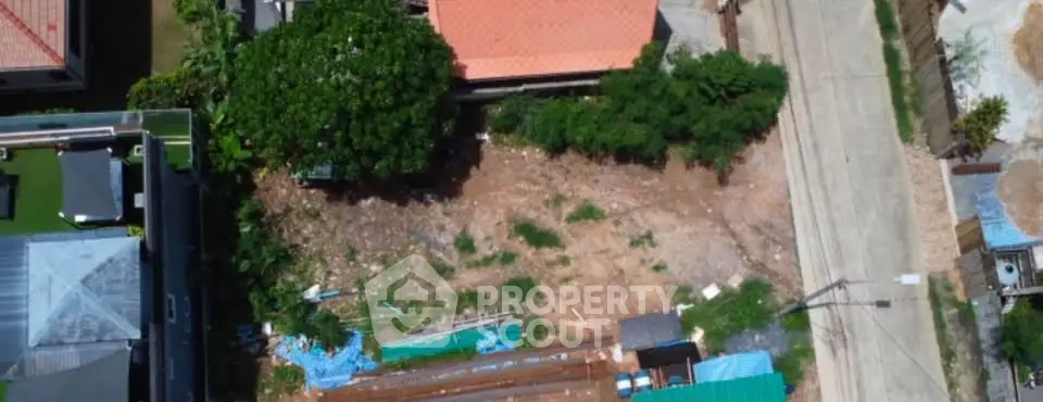 Aerial view of a residential plot with construction materials and surrounding houses.