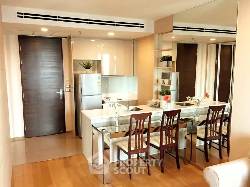 Modern kitchen with sleek design, mirrored wall, and dining area in a stylish apartment.