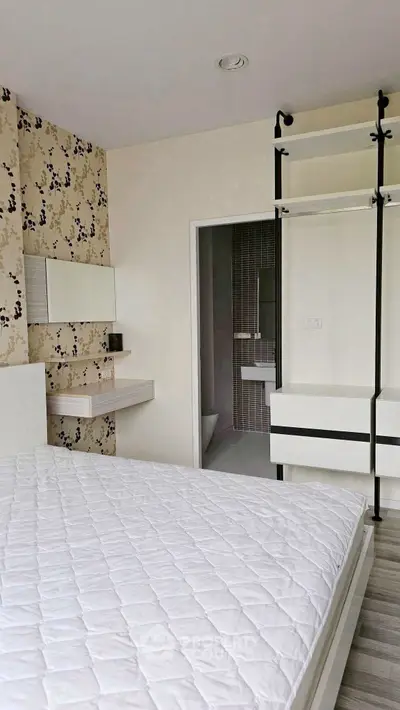 Modern bedroom with stylish wallpaper and open closet design, featuring a glimpse into a sleek bathroom.