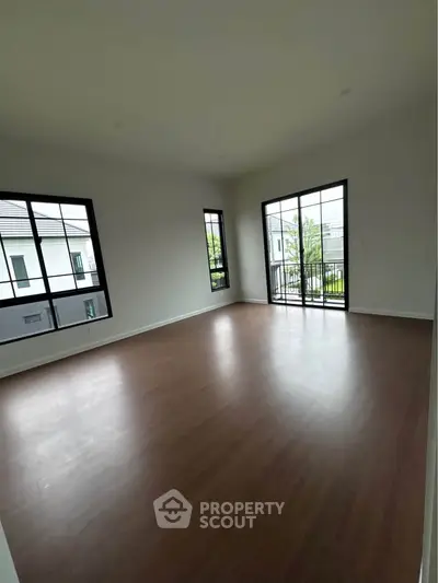 Spacious empty room with large windows and balcony access in modern home.