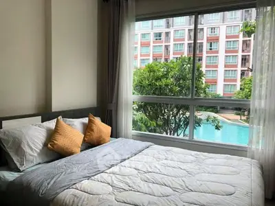 Spacious bedroom with large window offering pool view in modern apartment.