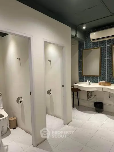 Modern bathroom with dual sinks and separate shower stalls, featuring sleek design and ample lighting.