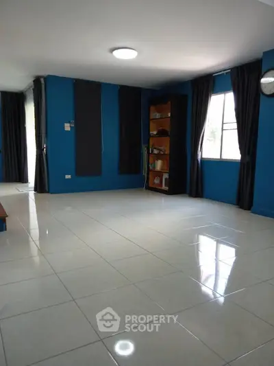 Spacious living room with blue walls and large windows offering natural light