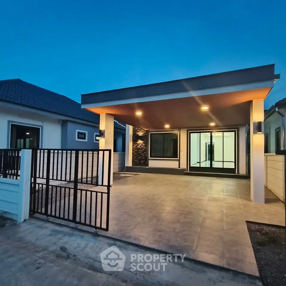 Modern single-story house with spacious driveway and elegant lighting at dusk.