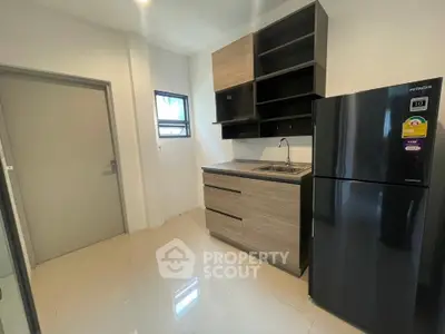 Modern kitchen with sleek cabinetry and stainless steel fridge in a compact layout.