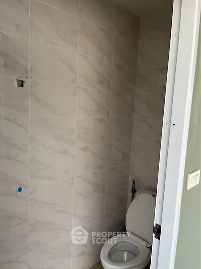 Modern bathroom with marble tiles and white toilet in a new property.