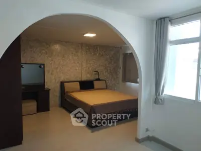 Spacious bedroom with elegant archway and large window for natural light