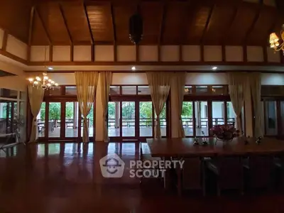 Spacious living room with wooden ceiling and large windows overlooking a lush garden.