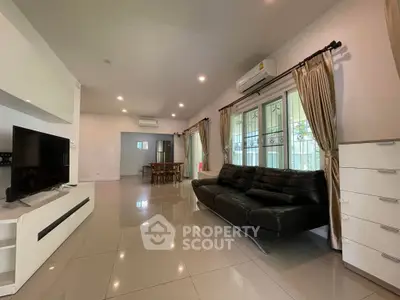 Spacious modern living room with sleek black sofa and large windows, perfect for family gatherings.
