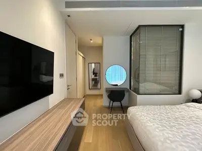 Modern bedroom with sleek design, featuring a wall-mounted TV, stylish furniture, and a cozy ambiance.