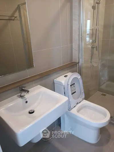 Modern bathroom with sleek fixtures and glass shower enclosure in contemporary apartment.