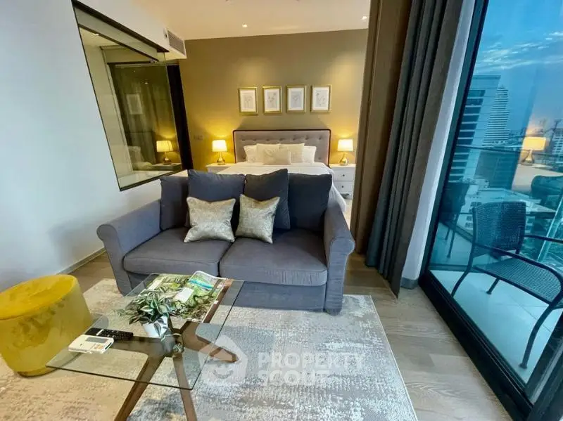 Modern studio apartment with cozy living area and stunning city view from balcony.