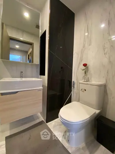 Modern bathroom with sleek design, featuring a stylish sink, toilet, and elegant marble walls.