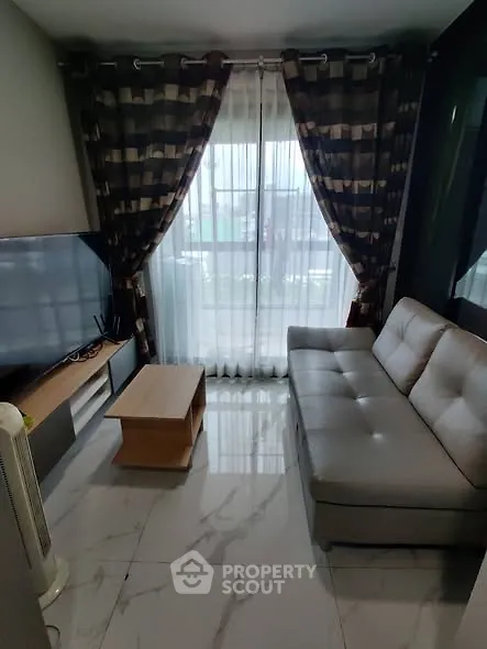 Modern living room with sleek sofa, marble flooring, and large window with elegant curtains.