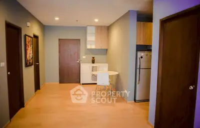 Modern apartment interior with wooden flooring and compact kitchen area.