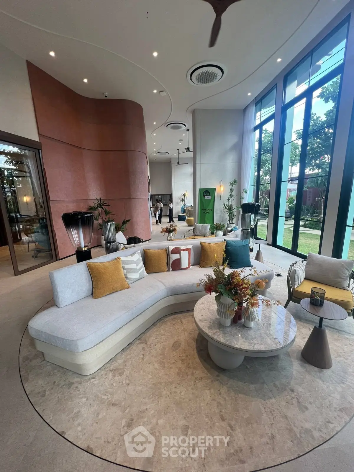 Luxurious modern living room with curved sofa and floor-to-ceiling windows offering garden views.