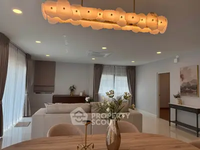 Elegant living room with modern lighting and stylish decor, featuring a cozy seating area and large windows.