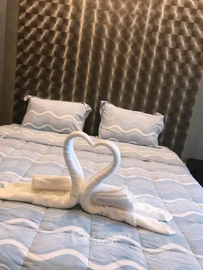 Luxurious bedroom with elegant bedding and decorative swan towels, perfect for a cozy retreat.