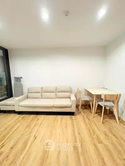 Modern living room with beige sofa and wooden flooring, perfect for cozy gatherings.