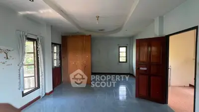 Spacious empty room with large windows and wooden doors, ideal for customization.