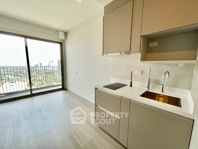 Modern kitchen with sleek cabinetry and city view from large window in high-rise apartment.
