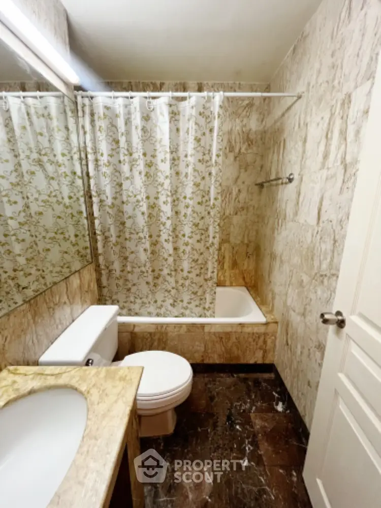Elegant bathroom with marble tiles and floral shower curtain in modern home.