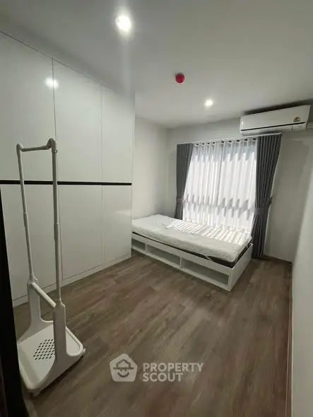 Modern minimalist bedroom with sleek white furniture and wooden flooring