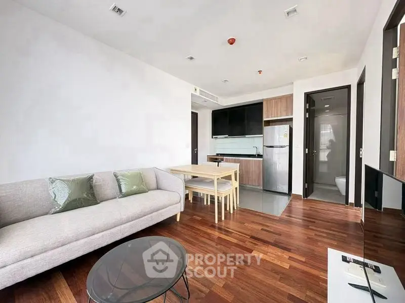 Modern open-plan living room with sleek kitchen and hardwood floors