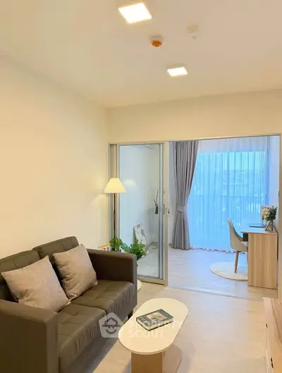 Modern living room with cozy sofa and sliding glass doors leading to a bright study area.